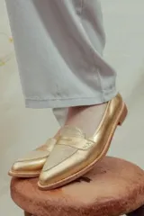 Mocasines de cuero plateado con acabado texturado, diseño clásico con costuras visibles y vira de suela natural cosida. Cuenta con taco plano de 2 cm y plantilla anatómica.
