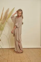 Conjunto de dos piezas color beige, compuesto por una blusa holgada de manga 3/4 con escote en V y detalles de lentejuelas, y un pantalón palazzo con aberturas laterales.