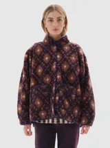 Campera de sherpa con estampado geométrico en tonos bordó y rosa, cuello alto, cierre frontal con broches a presión y bolsillos frontales con ribetes en contraste.