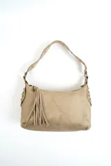 Bolso tipo hobo de gamuza color marrón, con diseño estructurado, asa de hombro con tachas metálicas y detalle de flecos colgantes en el lateral.