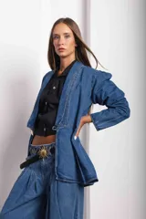 Blazer de denim azul con corte a la cintura, mangas largas con hombros ligeramente abullonados y cierre frontal mediante un botón de guampa.