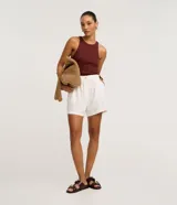 Short blanco de corte runner evasé, con cintura elástica fruncida y un botón decorativo. Presenta bolsillos laterales y un calce suelto.