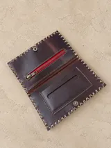 Billetera y tabaquera de cuero marrón con costuras decorativas artesanales en el contorno y cierre con botón a presión. Cuenta con compartimentos interiores para accesorios y tarjetas.