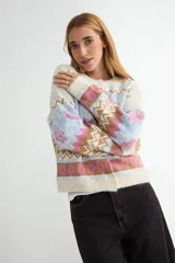 Cardigan de punto con diseño jacquard multicolor, cuello redondo y cierre frontal con botones. Presenta un patrón geométrico y floral en tonos verde, rojo, azul y crema.