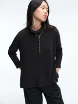 Buzo tejido de punto con cuello alto y sisa caída, de calce holgado y diseño relajado. Presenta tajos laterales en el ruedo y mangas largas.