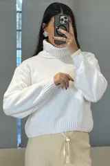 Buzo de chenille color blanco, con cuello alto tipo polera, mangas largas con puños ajustados y diseño de tejido acanalado.