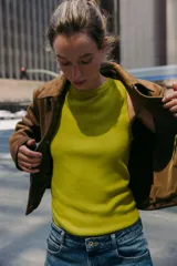 Top de punto color amarillo mostaza, con cuello redondo y manga sisa. Acabados en rib a tono.