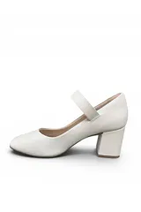 Zapato tipo Mary Jane de color blanco, con taco cuadrado medio y tira en el empeine con hebilla metálica dorada circular.