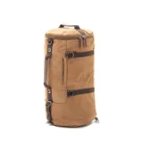 Bolso mochila de diseño cilíndrico confeccionado en tela canvas color verde oliva con detalles en cuero marrón. Cuenta con múltiples compartimentos, correas ajustables ocultables para usar como mochila, asas de mano y correa de hombro, con cierre vertical principal.