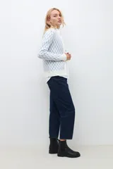 Cardigan de punto con diseño de rombos en color celeste sobre fondo blanco, cuello redondo y cierre frontal con botones.