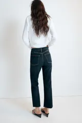 Jeans de tiro alto con cinco bolsillos, diseño cropped flare y bajo sin costuras. Cuenta con cierre frontal de cremallera y botón metálico.