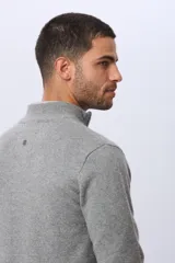 Buzo tejido de lana con cuello alto y medio cierre metálico frontal. Presenta puños y ruedo acanalados, con logo bordado en el pecho.