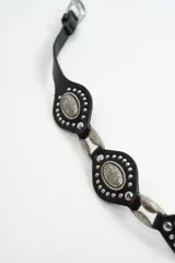 Cinturón negro de cuero con apliques metálicos plateados en forma de óvalo y hebilla metálica. Presenta el logo de la marca estampado en el extremo.