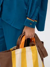 Pantalón de corte holgado y tiro alto con caída recta, color azul petróleo. Presenta una franja lateral decorativa en tonos rojo y amarillo que recorre la pierna, a juego con la camisa de la misma línea.