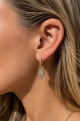 Aros tipo argolla pequeña de acero dorado con pavé de circonias y un dije colgante en forma de mano de Hamsa completamente engastado con circonias brillantes.