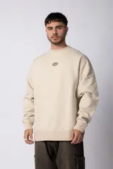 Buzo de cuello redondo y corte oversize, confeccionado en frisa suave. Presenta un diseño minimalista con un pequeño logo circular estampado en el centro del pecho.