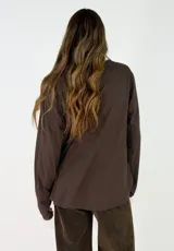 Blusa de manga larga en color blanco, con cuello redondo y detalle de alforzas verticales en el frente. Presenta un corte holgado y fluido.