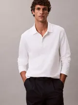 Chomba de manga larga Calvin Klein confeccionada en algodón interlock, con cuello clásico, cartera con botones y logo bordado en el pecho.