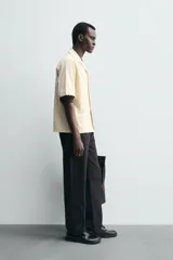 Camisa de corte relajado confeccionada en tejido de algodón, con cuello bowling y manga corta. Presenta un diseño con bordados geométricos a tono y cierre frontal de botones.