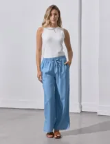 Pantalón celeste de lyocell, corte ancho, con pretina elastizada con lazo de ajuste, bolsillos verticales y ruedo desflecado.