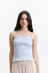 Musculosa de tiras finas color amarillo pálido, con textura elastizada y volados en el ruedo.