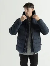 Campera acolchada con capucha integrada y cuello alto. Presenta cierre frontal con tirador reforzado, bolsillos laterales con cierre y terminaciones elásticas en puños y ruedo para mayor protección contra el frío.