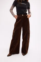 Pantalón cargo de pana color marrón oscuro, con corte amplio de pierna recta, bolsillos laterales con solapa y cierre frontal con botón.