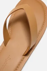 Sandalia minimalista de cuero negro, con tira delgada en el empeine y suela plana.