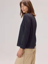 Remera de algodón con cuello redondo y manga larga. Presenta un diseño con costuras horizontales a la altura del pecho y costuras verticales en las mangas, brindando un detalle distintivo a la prenda.