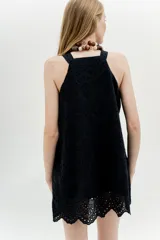 Vestido corto negro con bordado calado, sin mangas y corte evasé.