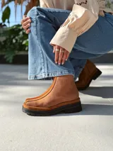 Botas cortas de cuero color marrón con elástico en los laterales y detalle de cuero texturizado en la parte delantera.