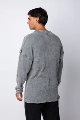 Buzo de corte oversize confeccionado en tela waffle de algodón con proceso de teñido acid wash. Presenta cuello redondo con detalle de costura en X y mangas largas con puños acanalados.