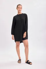 Vestido corto negro con cuello mao, abotonadura parcial y mangas largas abullonadas.