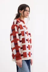 Sweater de tejido de punto con diseño geométrico a cuadros en tonos beige, terracota, bordó y celeste, de corte holgado, manga larga y cuello redondo.