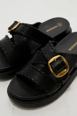 Sandalias planas de eco cuero color bordó, con tiras cruzadas y hebilla metálica dorada.
