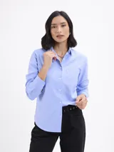 Camisa de corte clásico en tejido oxford color azul, con cuello camisero, cierre frontal de botones, manga larga con puños abotonados y un bolsillo frontal en el pecho.