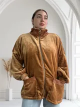 Campera de terciopelo color camel, con cierre frontal, cuello alto y bolsillos laterales con ribete de cuero sintético.