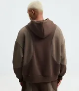 Saco cerrado con capucha, color marrón con recortes contrastantes en un tono más claro de marrón. Confeccionado en algodón y poliéster, tiene cordón para ajustar la capucha, bolsillos tipo canguro y manga larga.