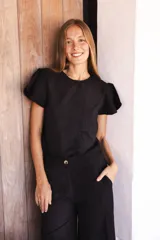 Blusa de lino color negro con bordado en relieve de formas orgánicas, cuello redondo y mangas cortas con terminaciones desflecadas.