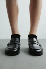 Mocasines estilo penny de color negro, con costura tradicional en la parte delantera y suela baja.