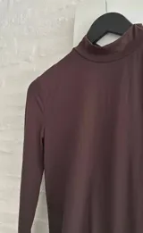 Vestido corto de manga larga con cuello alto, confeccionado en tejido elástico ajustado al cuerpo.