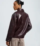 Campera bomber de poliuretano color marrón oscuro, con cuello clásico, cierre frontal con botones a presión, bolsillos delanteros con solapa, puños y bajo elásticos, y recortes estructurados.