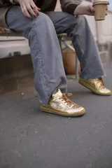 Championes dorados de cuero metalizado con detalles de gamuza, suela de caucho y cordones marrones.