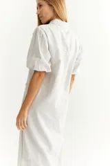 Vestido camisero midi de lino a rayas verticales grises y blancas, con cuello camisero, mangas cortas abullonadas, cierre frontal con botones y bolsillos laterales.