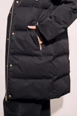 Tapado negro largo con capucha, diseño capitoneado y cierre frontal con botones dorados.