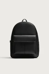 Mochila de diseño minimalista en color negro con acabado texturizado. Cuenta con un compartimento principal con cierre de cremallera, un bolsillo frontal con solapa y compartimento interior para dispositivos electrónicos. Incluye espalda acolchada, banda de sujeción para equipaje, asa de mano y correas de hombro ajustables.