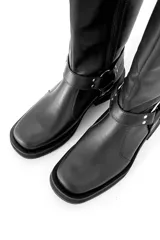 Bota alta de cuero negro con caña alta y hebillas plateadas.