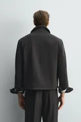 Cazadora de corte cropped confeccionada en tejido de mezcla de lana. Presenta cuello solapa, cierre frontal con cremallera, bolsillos de vivo en la cadera y mangas largas con puños abotonados. Incluye forro interior a contraste y bolsillo interior.