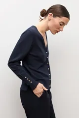 Cardigan negro con escote en V, manga larga y cierre frontal con botones pequeños. Presenta puños acanalados con detalle de botones decorativos.
