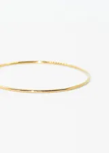 Pulsera esclava de acero quirúrgico hipoalergénico color dorado, de caña redonda y diseño minimalista.